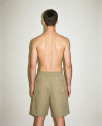 thirdofthefifth pleated breathable cotton shorts in muted earthy tone featuring front pleats, elasticated waistband, relaxed tailored fit, and above-knee silhouette designed for warm-weather dressing. unisex