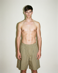 thirdofthefifth pleated breathable cotton shorts in muted earthy tone featuring front pleats, elasticated waistband, relaxed tailored fit, and above-knee silhouette designed for warm-weather dressing. unisex